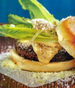 A Caesar salad burger--hamburger on a bun with melted cheese, Parmesan cheese, romaine lettuce and Caesar mayonnaise