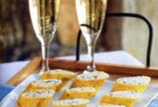 A platter of herb omelettes stuffed with ricotta on a wooden tray with two glasses of Champagne.