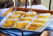 A platter of herb omelettes stuffed with ricotta on a wooden tray with two glasses of Champagne.