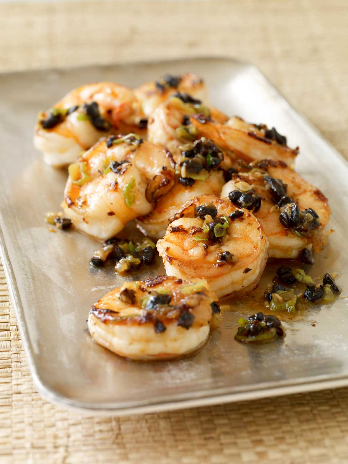 Shrimp with black beans piled on a rectangular metal tray.
