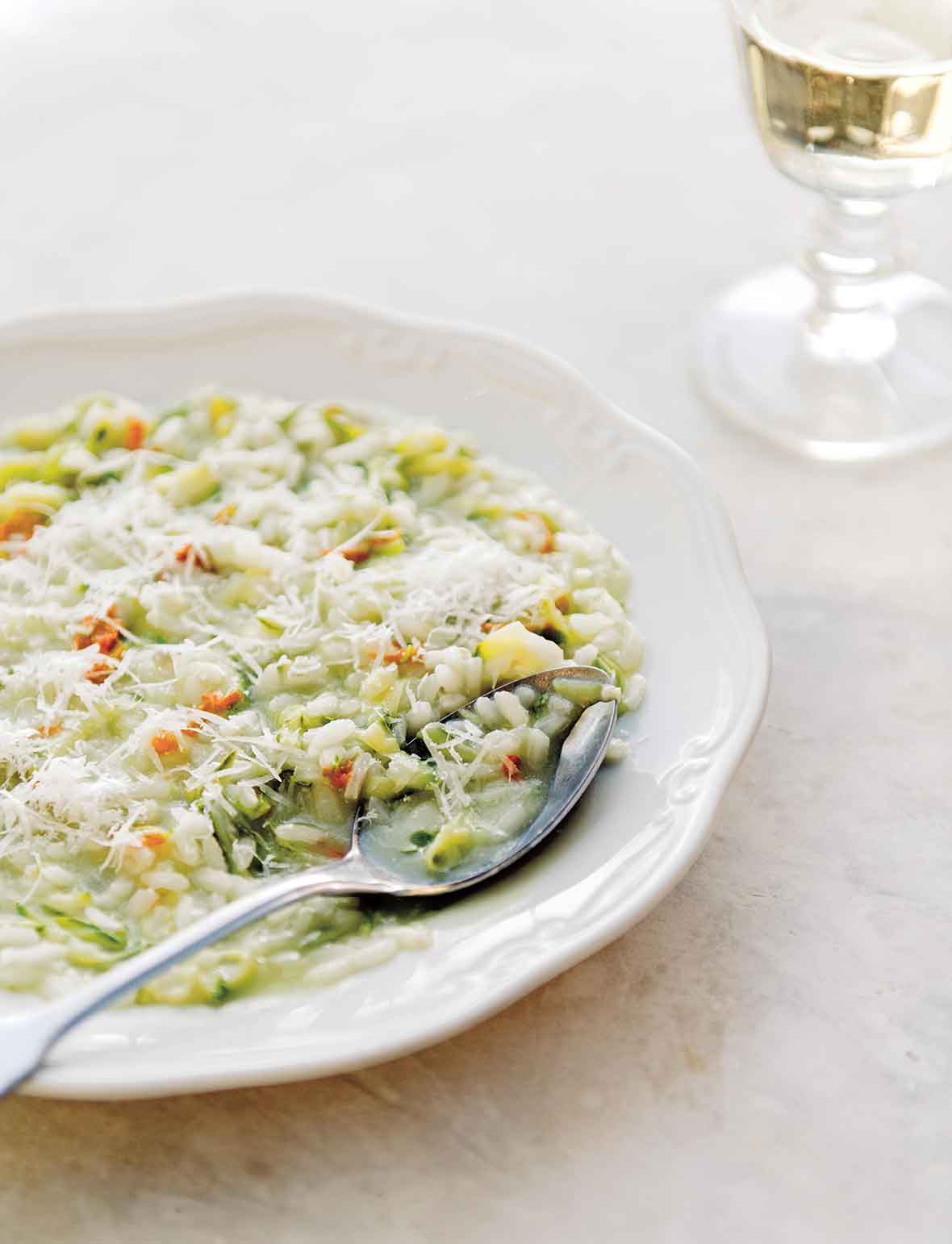 A bowl filled with zucchini risotto and a spoon resting inside.