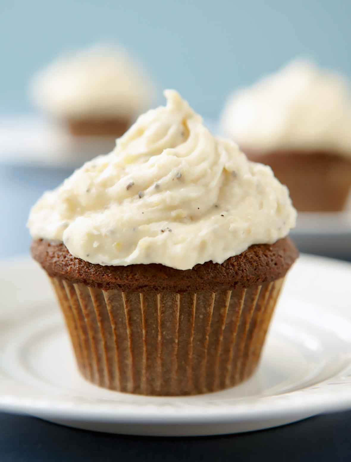 Gingerbread cupcakes with cardamom cream cheese frosting on a white plate.
