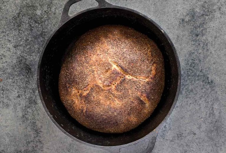 Cast-iron pot with a loaf of Jim Lahey's no-knead whole-wheat bread on a gray background