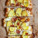 A sliced oval-shaped potato bacon pizza.
