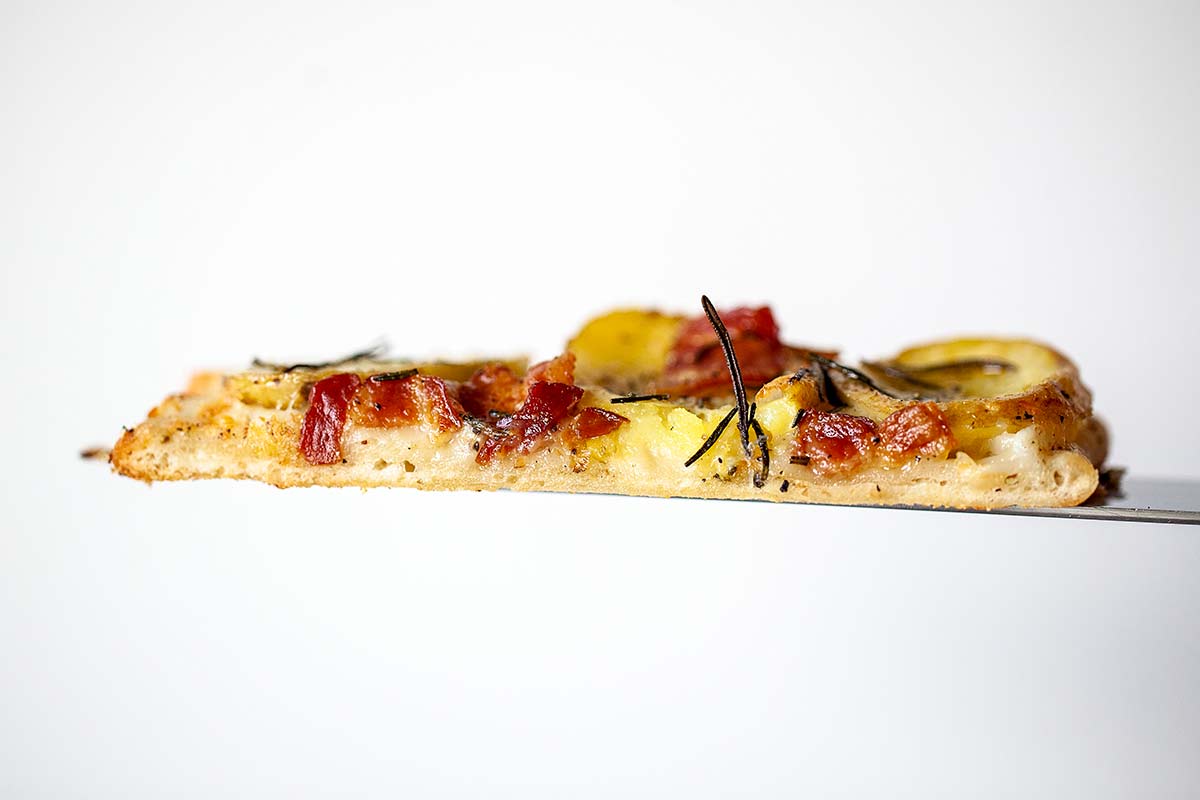 A slice of potato bacon pizza on a peel.