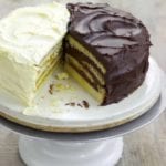 Cake stand with a half of a lemon Doberge layer cake and a half of a chocolate Doberge layer cake