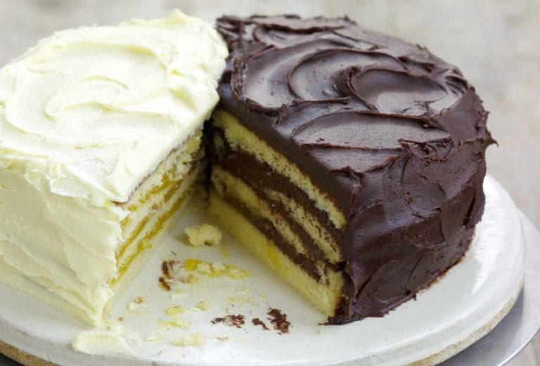 Cake stand with a half of a lemon Doberge layer cake and a half of a chocolate Doberge layer cake