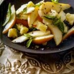 Pear basil pecorino Toscano salad in a large brown serving bowl on a carved wooden tray