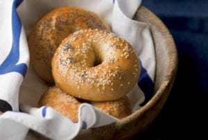 Basket of homemade bagels topped with sesame seeds and poppy seeds