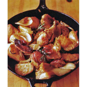 Chicken, potatoes, and bacon in a cast-iron skillet, garnished with rosemary sprigs.