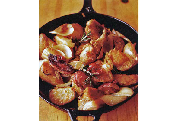 Chicken, potatoes, and bacon in a cast-iron skillet, garnished with rosemary sprigs.