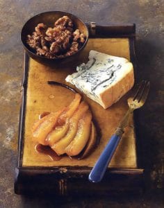 A slab of Gorgonzola dolce on a wooden cutting board with a fanned, roasted oear