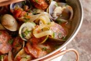 A cataplana with slices of spicy chouriço sausage and sweet clams in a tomato-onion broth