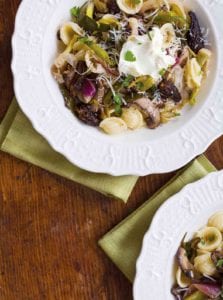 Two white ceramic bowls filled with orecchiette with morel mushrooms and ramps and a dollop of mascarpone.
