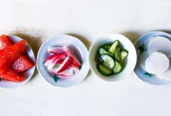 Four bowls of salt and sugar pickles; one with watermelon, one with red radish, one with cucumber, and one with daikon radish.