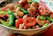 Bowl of cashew chicken with chunks of stir-fried chicken, carrots, sugar snap peas, celery, cashews.