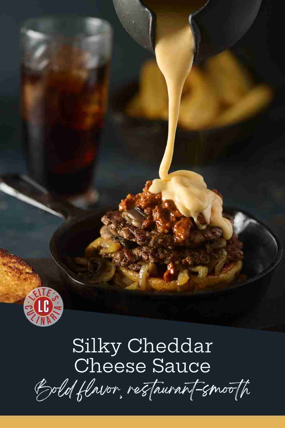 Creamy cheddar cheese sauce pouring from a black pitcher onto a double patty burger with mushrooms and onions.