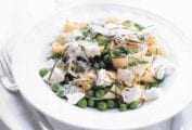 A white bowl filled with lemon, ricotta, and pea pasta.