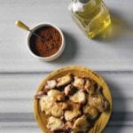 Wooden bowl of octopus with paprika, bowl of paprika, cruet of olive oil