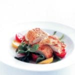 White bowl of sliced parmesan-crusted chicken, lettuce, and red and yellow cherry tomatoes