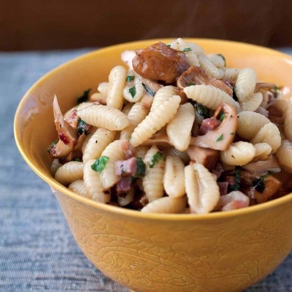 A bowl of gnocchetti pasta, with ham, chanterelles, and mint.