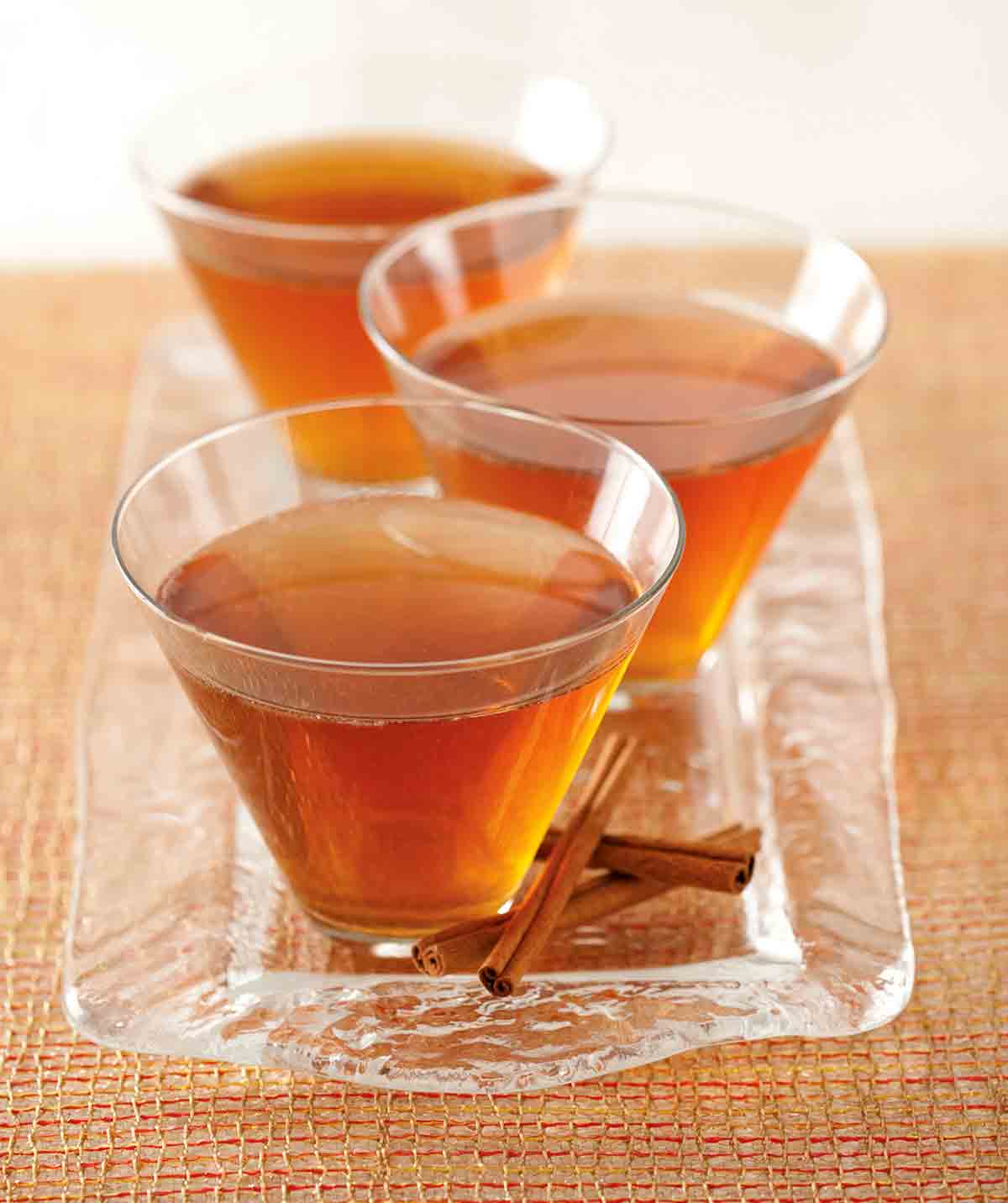 Three glasses of Maple Leaf Cocktails on a glass tray with cinnamon sticks