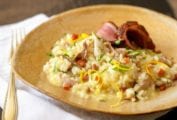 A wide ceramic bowl filled with Portuguese duck risotto, topped with orange zest and parsley.