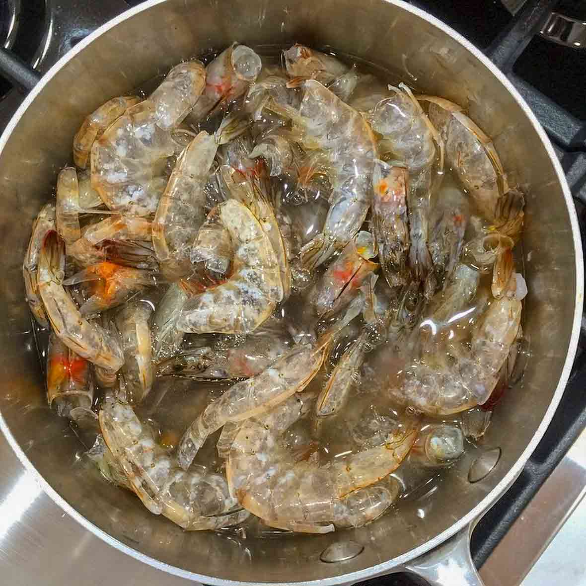 A pot filled with shrimp shells and heads, all to make shrimp stock