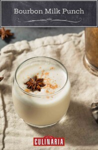A glass filled with white bourbon milk with cinnamon sprinkled on top and with a star anise floating in the glass.
