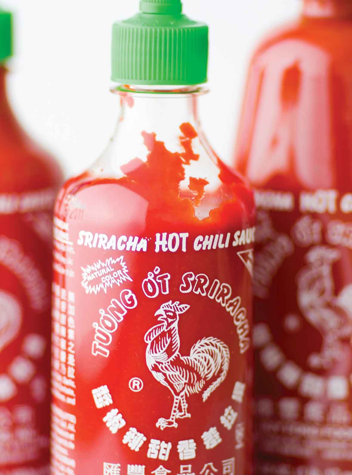 Three bottles of homemade Sriracha sauce.