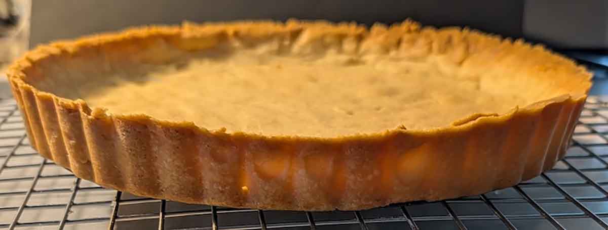 A fresh-out-of-the-oven p&acirc;te sucr&eacute;e (sugar crust) tart shell cooling on a wire rack.