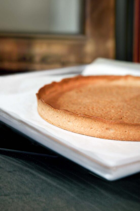 A crisp pate sucree tart crust cooling on a baking sheet.