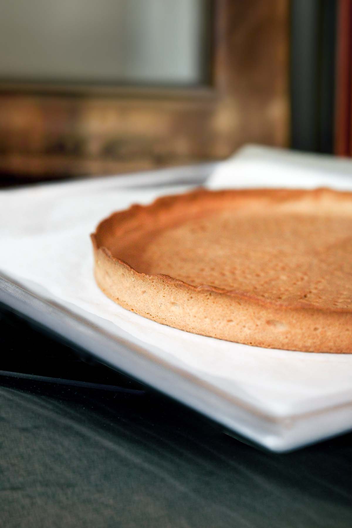 A crisp pate sucree tart crust cooling on a baking sheet.