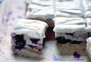 Squares of blueberry tea cake topped with cream cheese frosting.