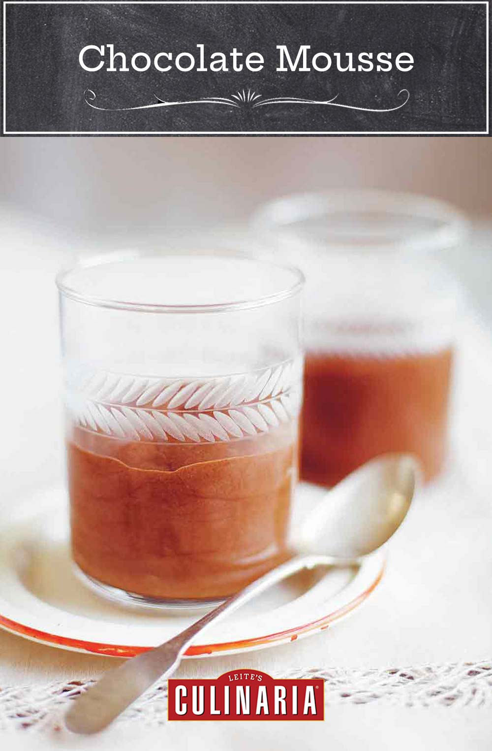 Two individual servings of chocolate mouse in glass tumblers served on a small plate with a silver spoon resting beside.