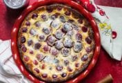 A cherry clafouti in a red dish with cherry dish towels