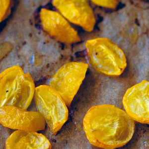 Cut yellow roasted cherry tomatoes on a sheet of parchment paper.