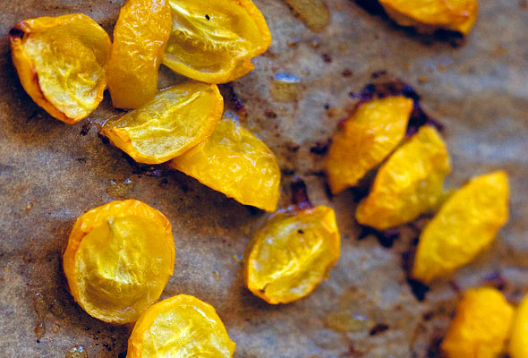 Cut yellow roasted cherry tomatoes on a sheet of parchment paper.