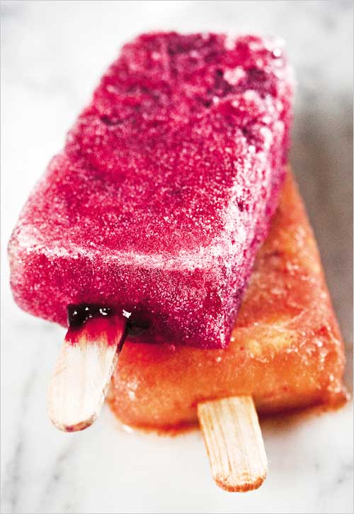 A hibiscus ice pop lying on top of a spicy mango ice pop.
