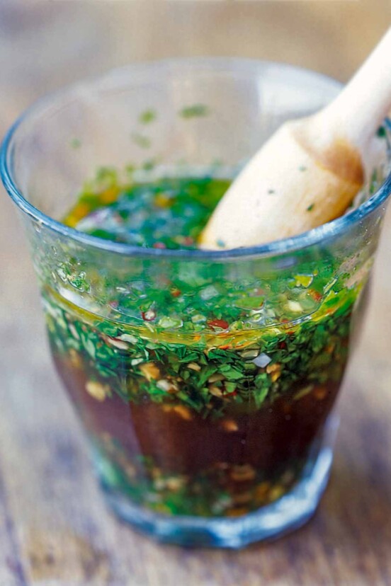 A glass full of chimichurri--an Argentine steak sauce--made with vinegar, olive oil, parsley, oregano, garlic, red pepper flakes