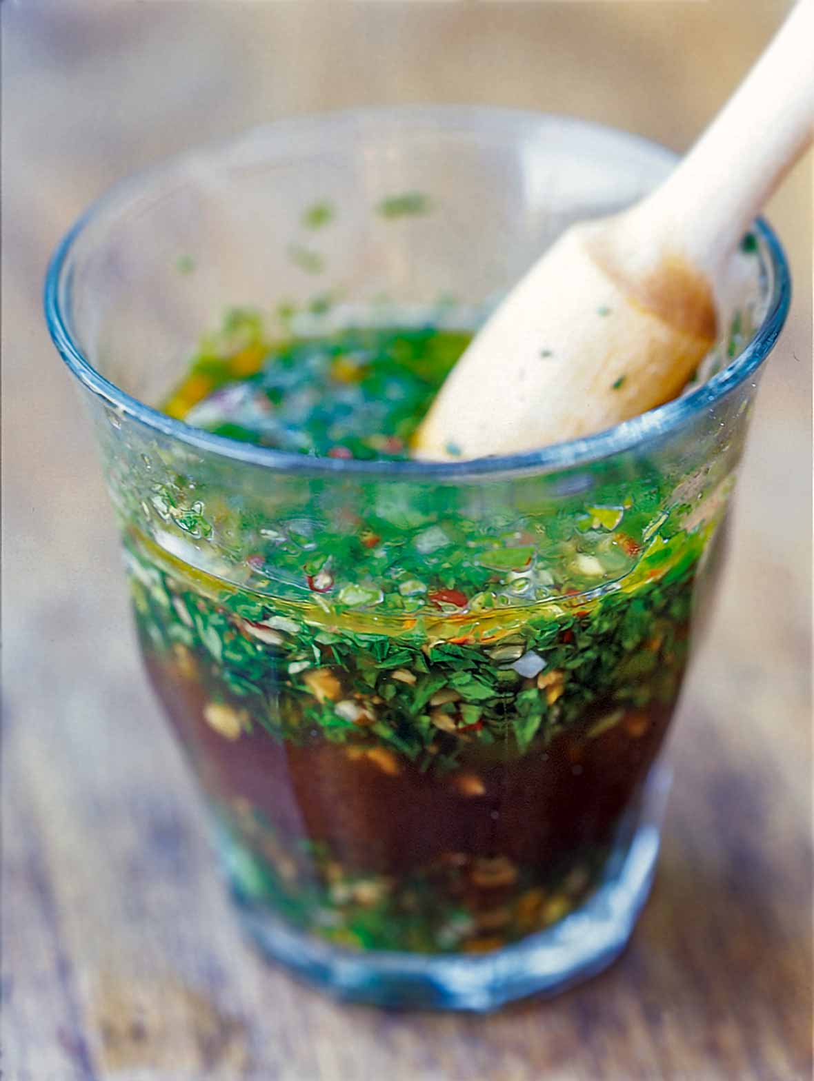 A glass full of chimichurri--an Argentine steak sauce--made with vinegar, olive oil, parsley, oregano, garlic, red pepper flakes