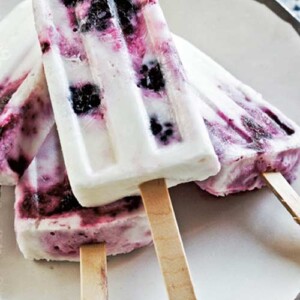 Yogurt ice pops with berries stacked on a white plate.