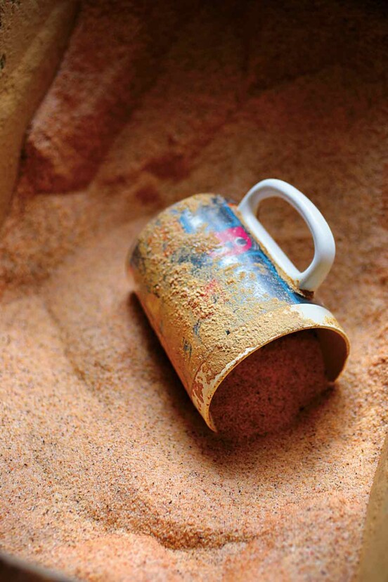 A mug lying on its side in a bin of cajun spice mix