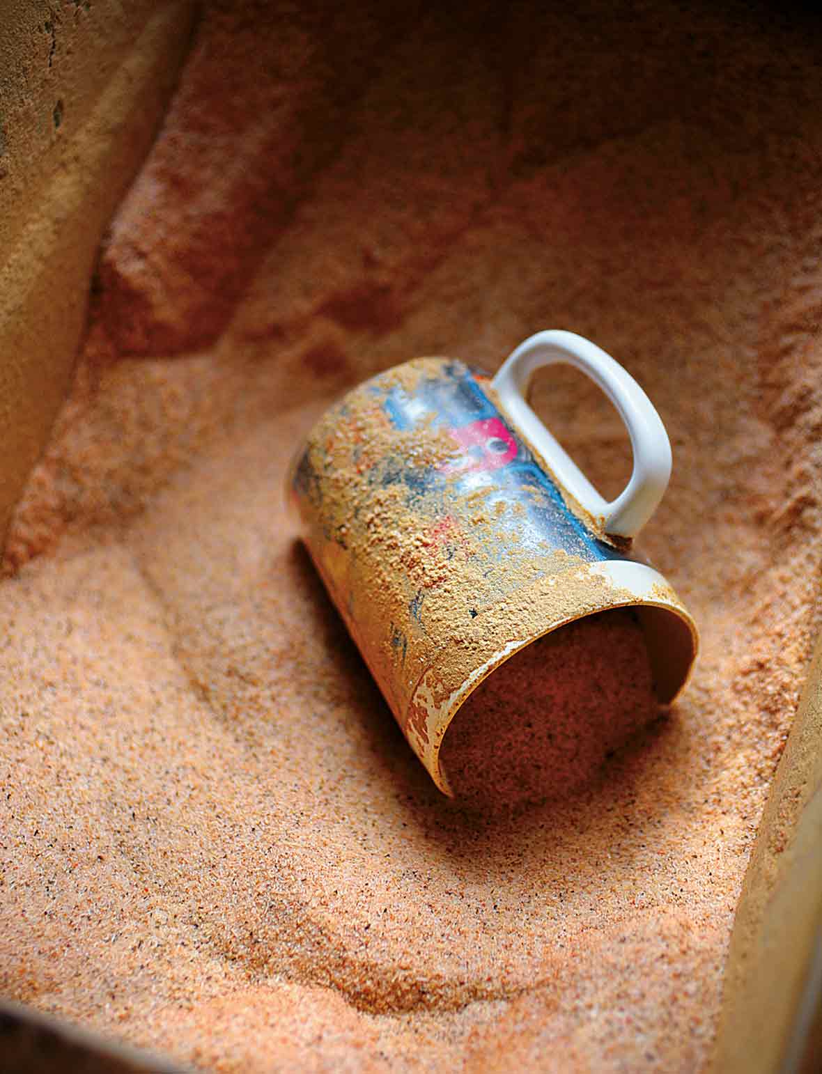 A mug lying on its side in a bin of cajun spice mix