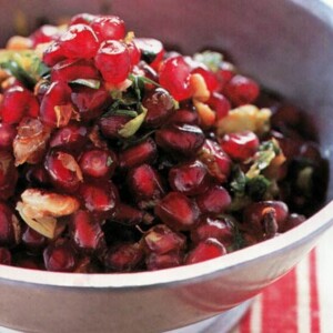 Pomegranate Walnut Relish in a white bowl on a red and white placemat.