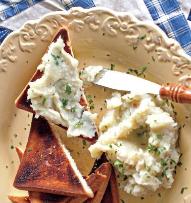 Smoked whitefish brandade slathered on toast points, on a white plate with a knife.