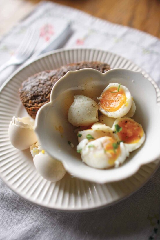 Halved soft-boiled eggs and toast on a plate with egg shells.
