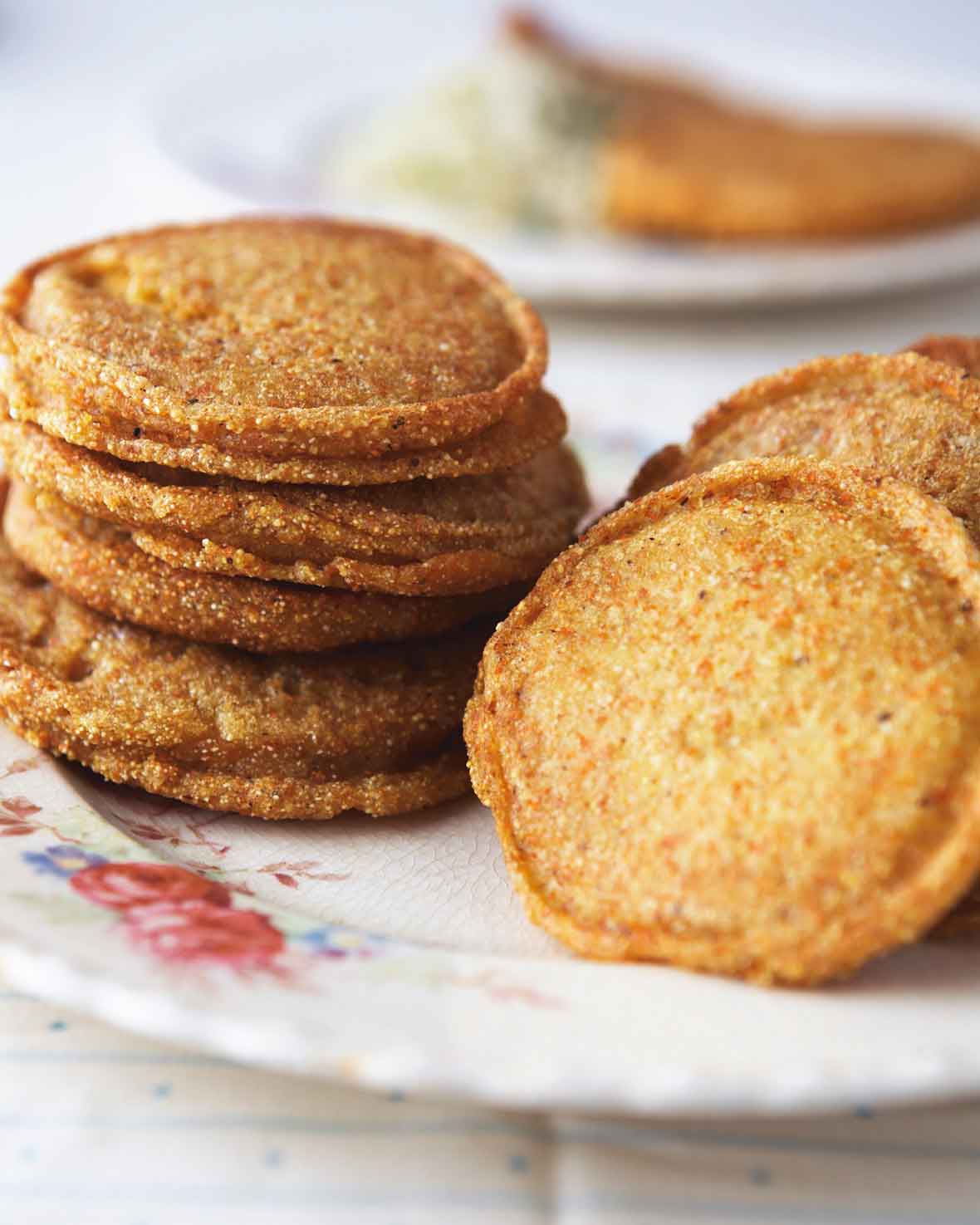 Two stacks of cornmeal griddle cakes on a patterned plate.