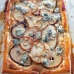 A pear tart with blue cheese and honey finished with sliced almonds.