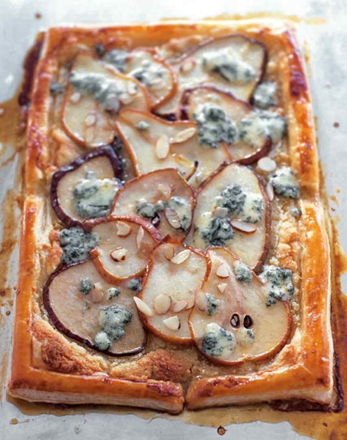 A pear tart with blue cheese and honey finished with sliced almonds.